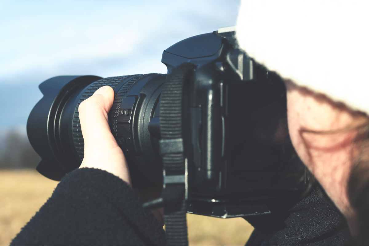 Dziewczyna w białej czapce robi zdjęcie aparatem fotograficznym - lustrzanką